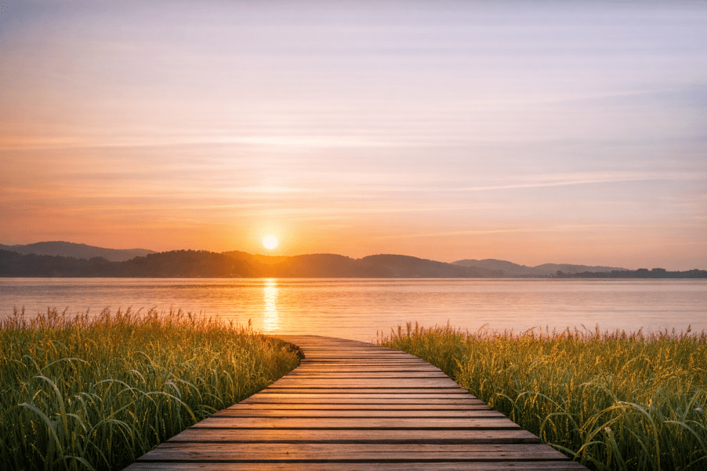 Wooden boardwalk leading toward calm water at sunset, symbolizing clarity and direction”
